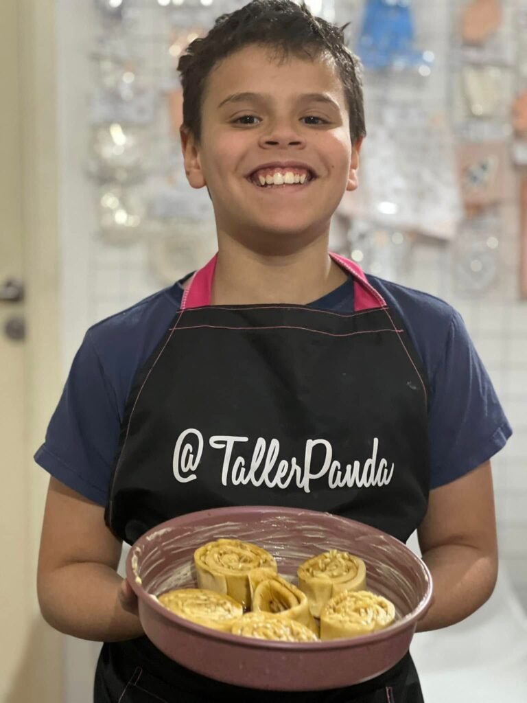Niño con delantal de Taller Panda mostrando su trabajo