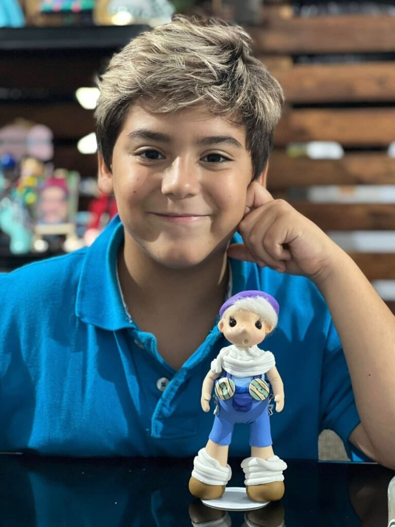 Niño sonriendo junto a la figura que modeló